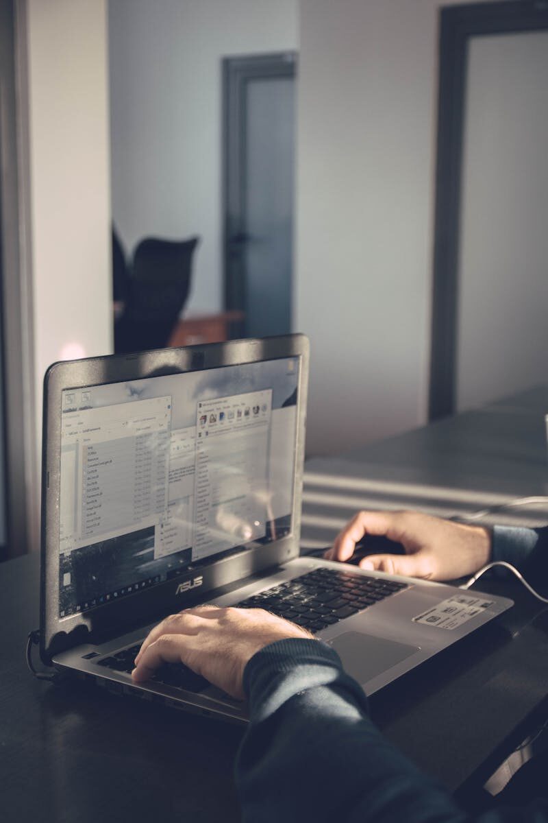 A person typing on a laptop inside an office, emphasizing technology and productivity.